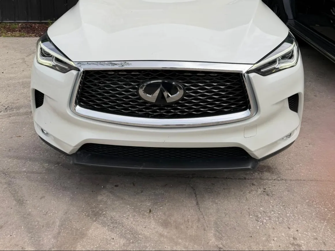 The same white Infiniti QX50 back together, grille, bumper and hood aligned, parked outside the shop.