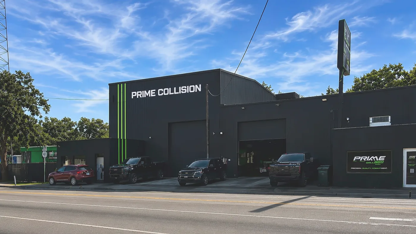 The Prime Collision shop on North Nebraska Avenue in Tampa: a black building with green stripes and the Prime Collision name above the bay doors, under a blue sky.