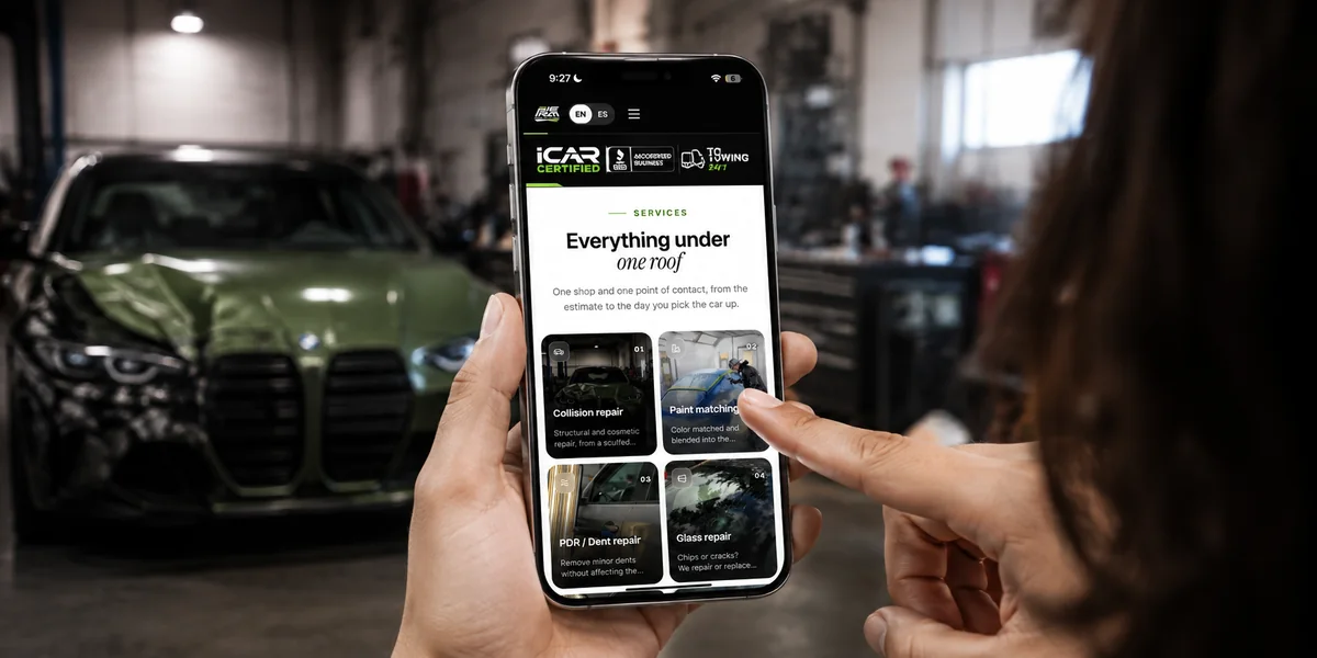 The Prime Collision website open on a phone inside the shop, with a damaged BMW behind it.