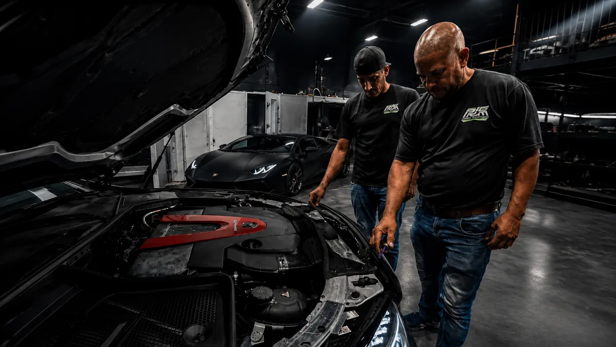 Two Prime Collision technicians looking over an open engine bay inside the shop.